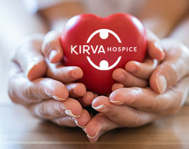 An adult cupping their hands with a child's hand cupped on top holding a red heart with the Kirva Hospice logo on it.